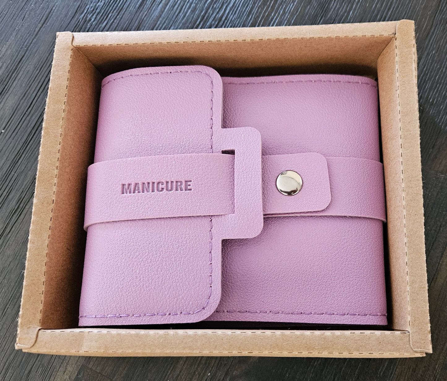 Pink leather wallet in a cardboard box on a wooden surface