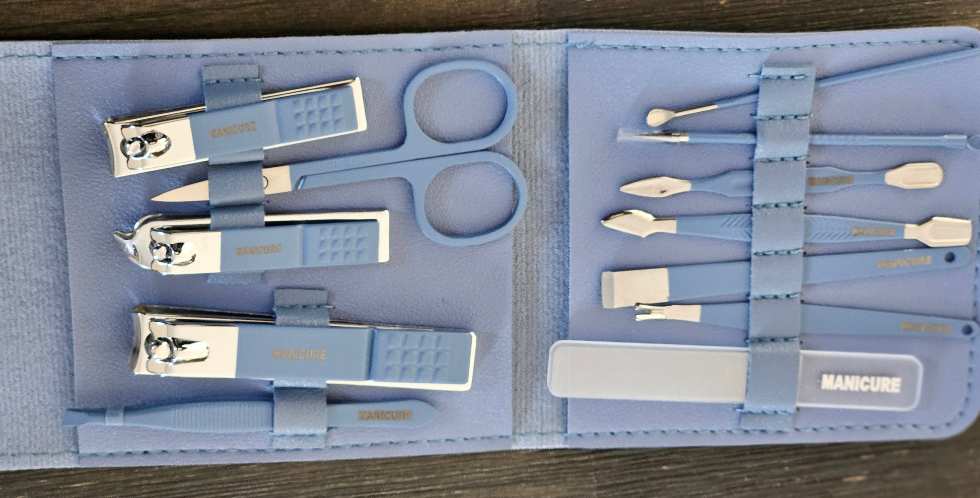 Manicure set with various tools in a blue case on a wooden surface